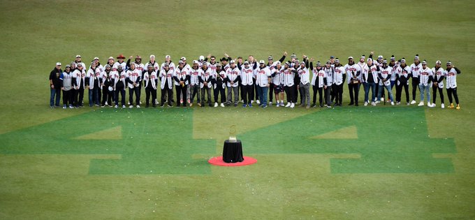 The entire 2021 Atlanta Braves surround the “44” painted in centerfield along with the World Series trophy