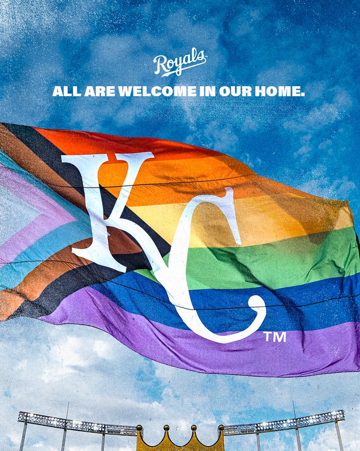 A graphic featuring the Pride flag with the Kansas City Royals logo waving in the air above CrownVision against a blue sky. Text on the graphic reads, "All are welcome in our home" with a Royals logo above it.