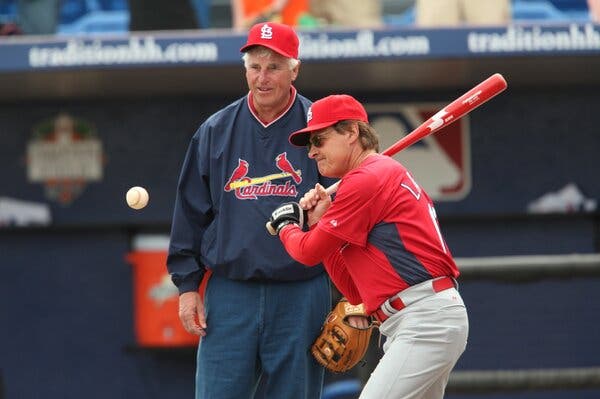 Bobby Knight watches over Tony La Russa’s shoulder as he prepares to hit a baseball.