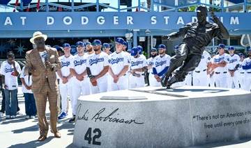 A photo of Bob Kendrick, the President of the Negro Leagues Museum, speaking to Dodger and Mets players next to the Jackie Robinson statue.