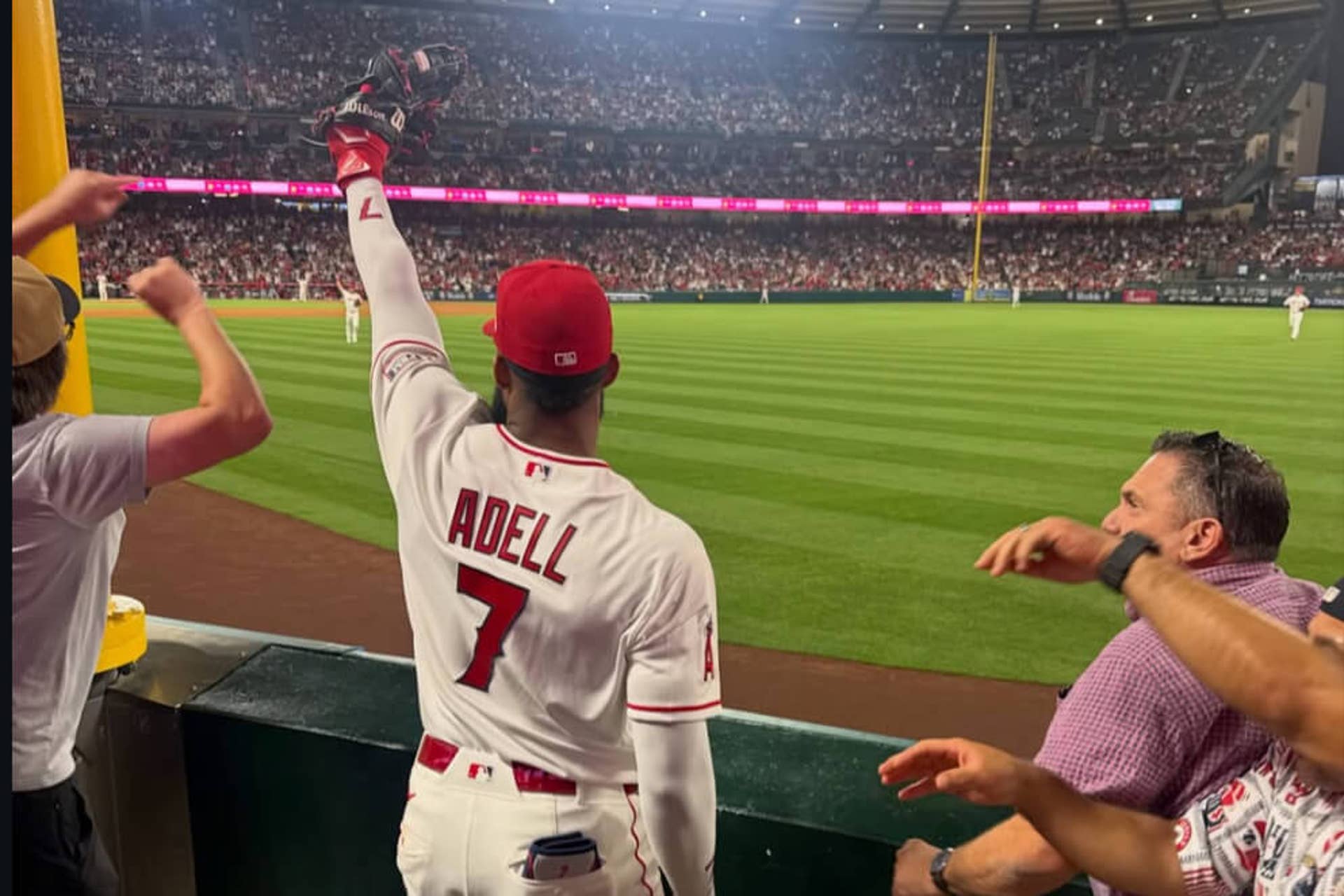 Jo Adell holds a ball in his glove while standing in the right-field seats after a home-run-stealing catch.